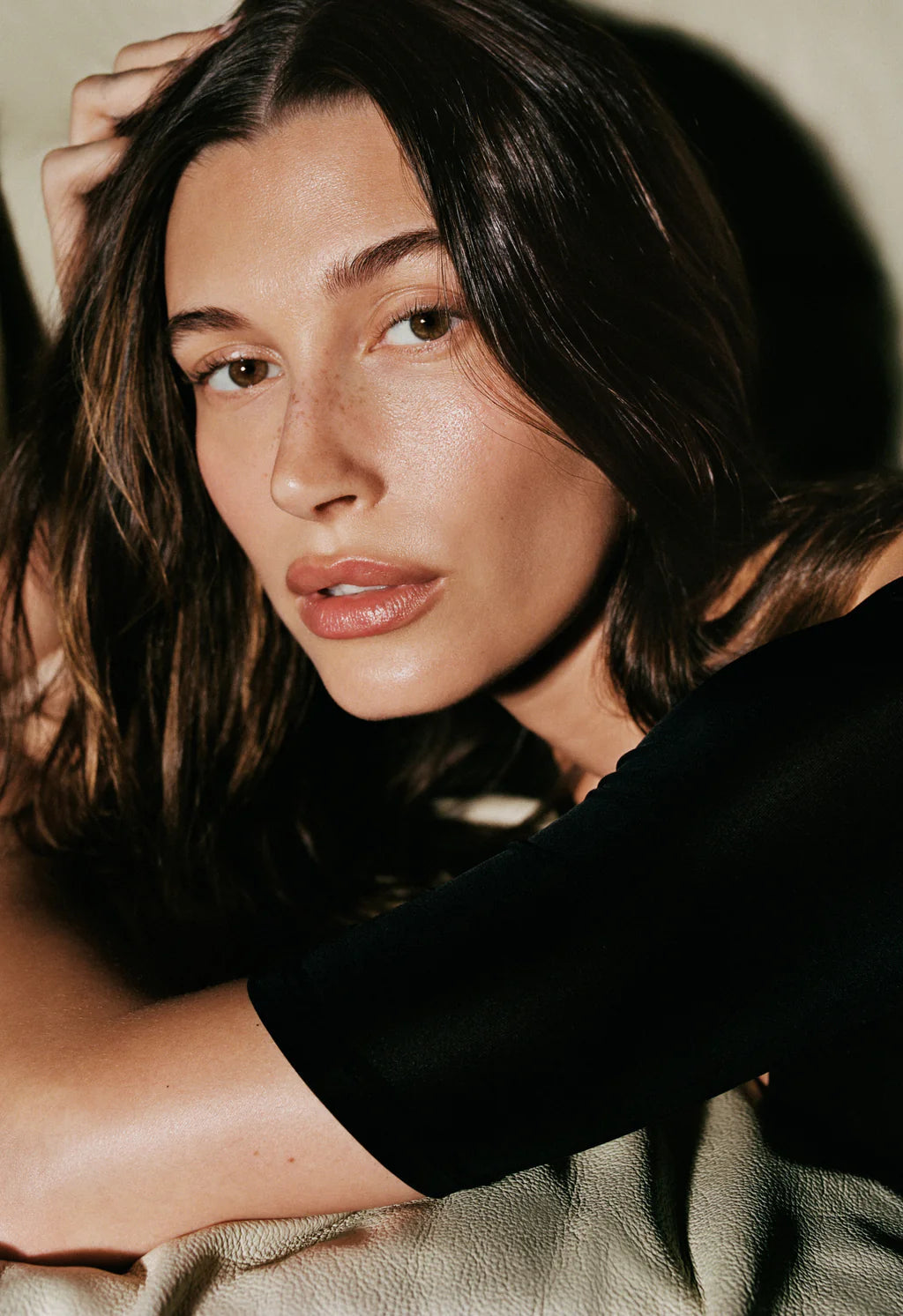 Model with glowing skin holding Rhode Glazing Milk