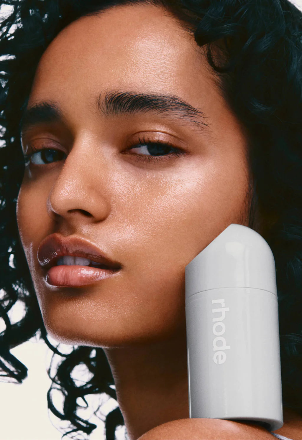 Model holding Rhode Peptide Glazing Fluid with glowing skin